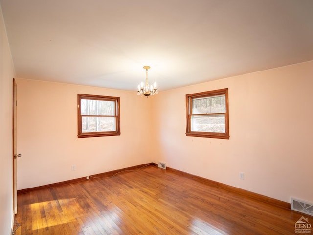 unfurnished room with hardwood / wood-style flooring and a notable chandelier