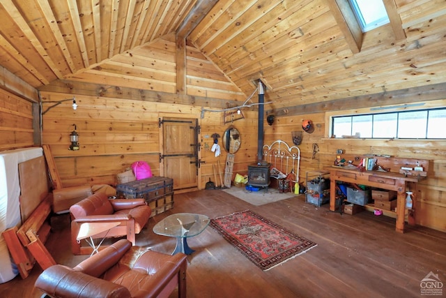 interior space featuring lofted ceiling with skylight, wood ceiling, wood walls, and a wood stove