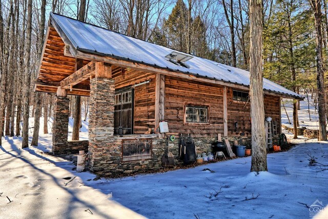 view of snow covered exterior with metal roof and stone siding