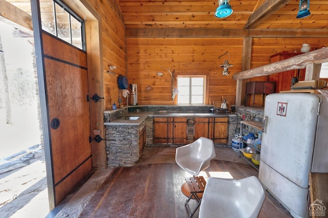 kitchen featuring dark wood-style floors, dark countertops, wooden walls, and brown cabinetry