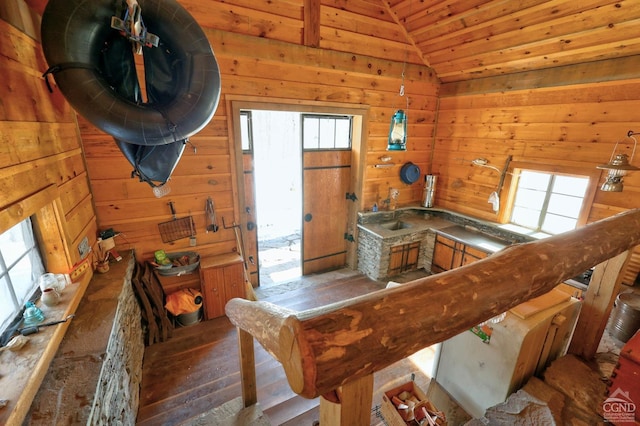 interior space featuring a sink, hardwood / wood-style floors, wooden ceiling, wood walls, and lofted ceiling