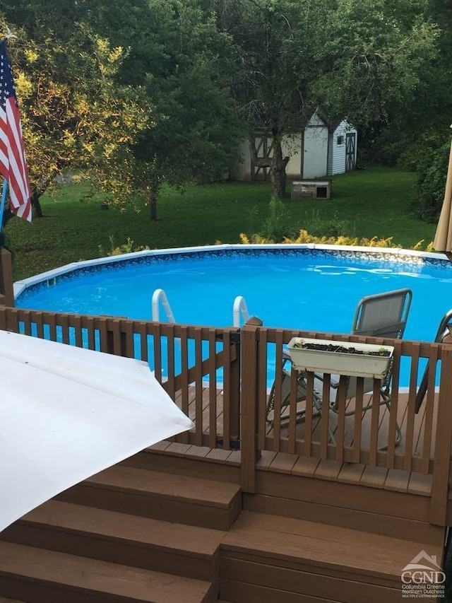 view of swimming pool with a shed, a yard, and a wooden deck