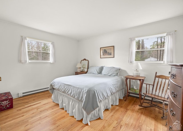 bedroom featuring baseboard heating, wood finished floors, a baseboard heating unit, and multiple windows
