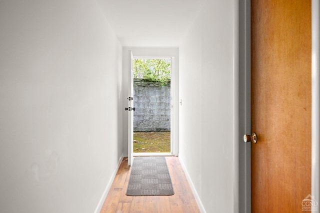 doorway to outside with light wood finished floors and baseboards