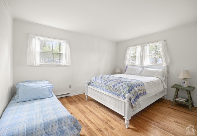 bedroom with baseboard heating, baseboards, ornamental molding, and light wood-style floors
