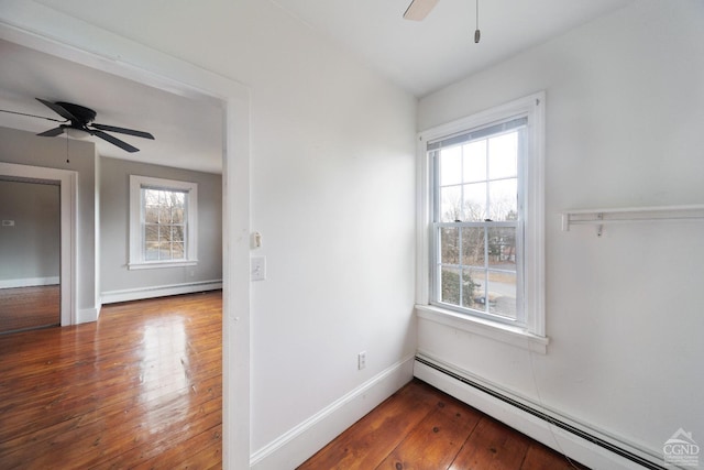 unfurnished room with ceiling fan, dark hardwood / wood-style flooring, and a baseboard heating unit