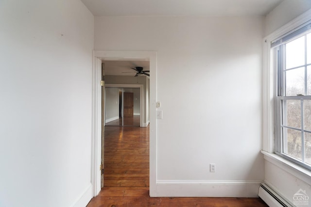 spare room with dark wood-style floors, a baseboard radiator, and a wealth of natural light