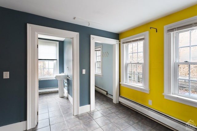 interior space featuring light tile patterned floors, a baseboard radiator, baseboards, and baseboard heating