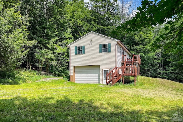 rear view of property with a wooden deck, a yard, and a garage