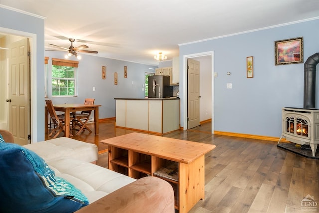 living room featuring a wood stove, ceiling fan, light hardwood / wood-style floors, and ornamental molding