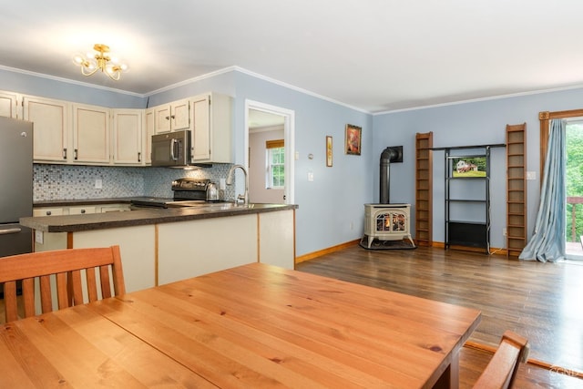 kitchen featuring a wood stove, crown molding, decorative backsplash, dark hardwood / wood-style flooring, and stainless steel appliances