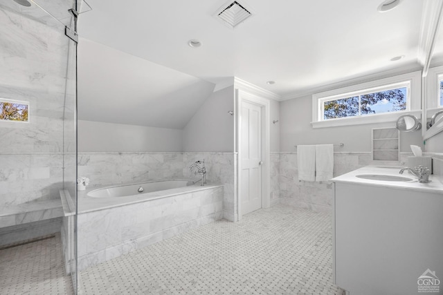 bathroom featuring tile patterned flooring, tiled tub, vaulted ceiling, vanity, and tile walls