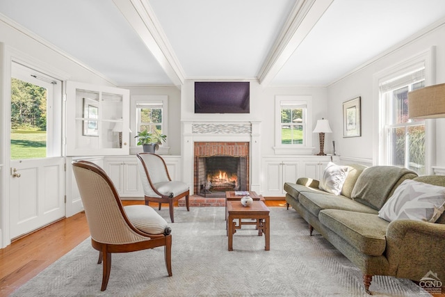 living room featuring a brick fireplace, a wealth of natural light, ornamental molding, and light wood-type flooring