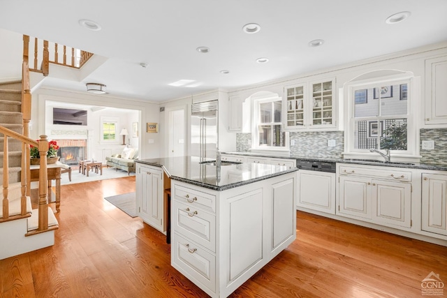 kitchen with decorative backsplash, white cabinetry, light hardwood / wood-style flooring, a kitchen island, and built in fridge