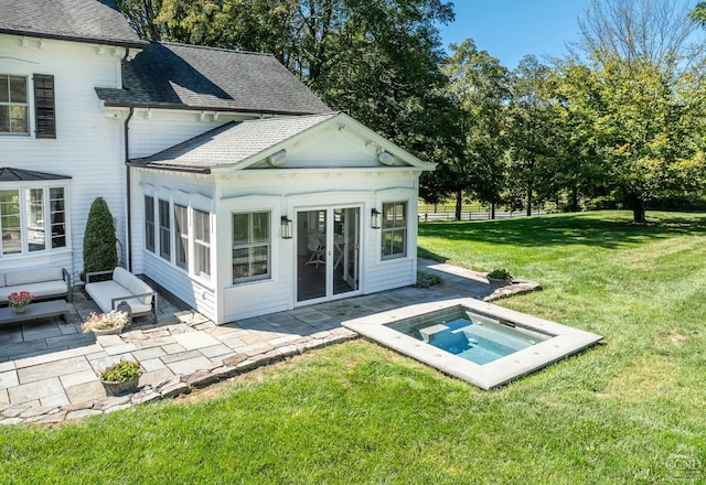 rear view of house featuring an in ground hot tub, a yard, and a patio area