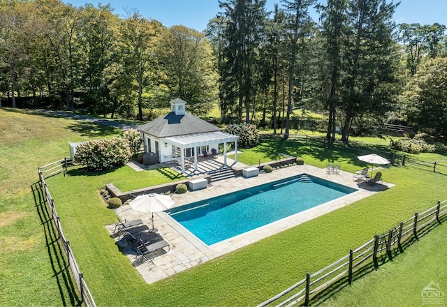 view of swimming pool featuring a yard, an outbuilding, a patio, and a rural view