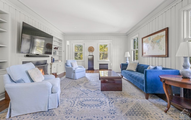 living room featuring built in shelves, a wealth of natural light, and crown molding