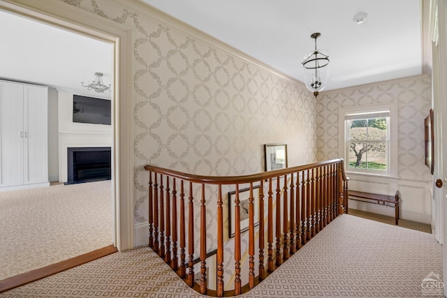 hallway featuring carpet flooring, a notable chandelier, and ornamental molding