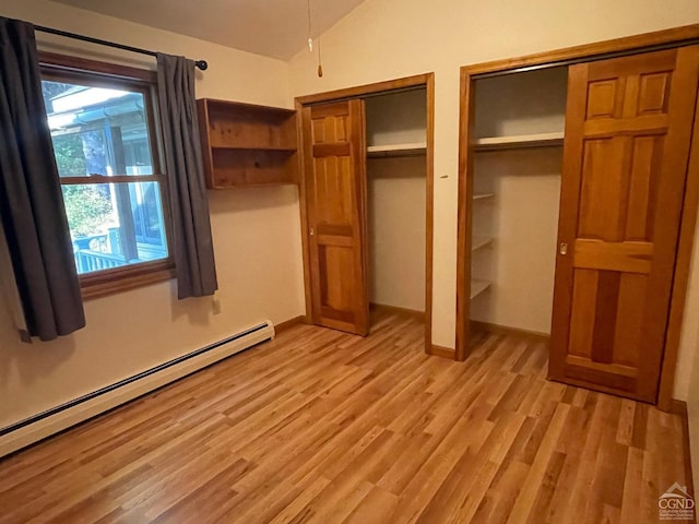 unfurnished bedroom featuring lofted ceiling, multiple closets, light hardwood / wood-style flooring, and a baseboard heating unit