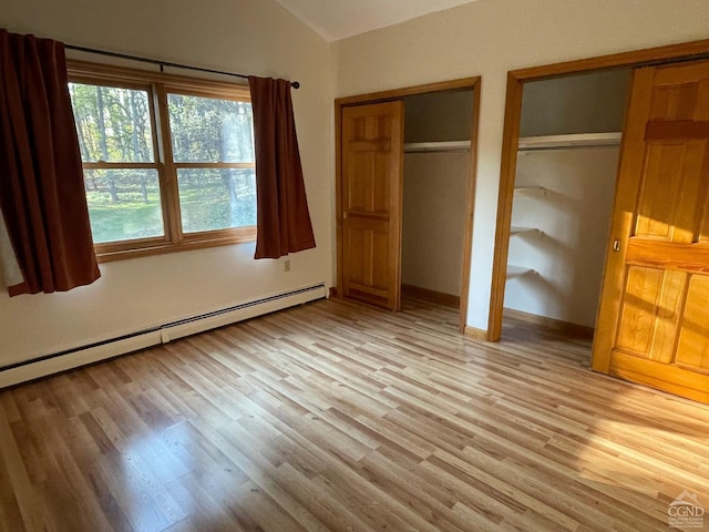 unfurnished bedroom with multiple closets, light hardwood / wood-style flooring, a baseboard radiator, and vaulted ceiling