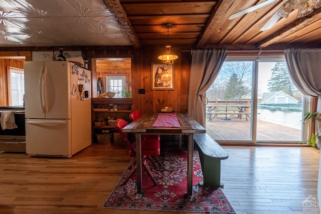 dining area with a wealth of natural light, wooden walls, and hardwood / wood-style floors