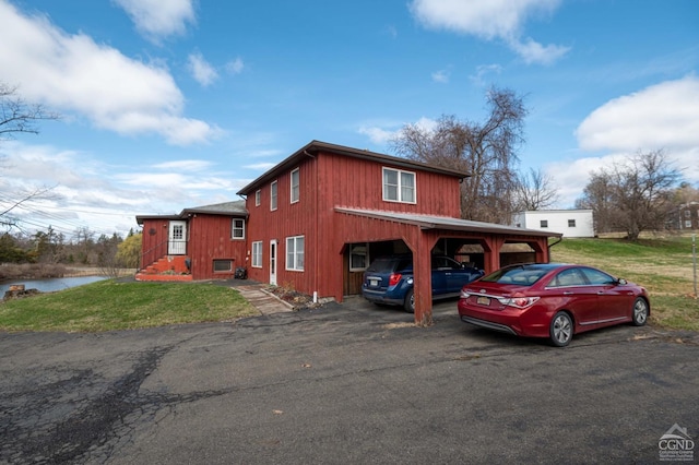 view of front of home with a front lawn, driveway, and a water view