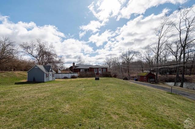 view of yard featuring a storage unit, a deck, and an outbuilding