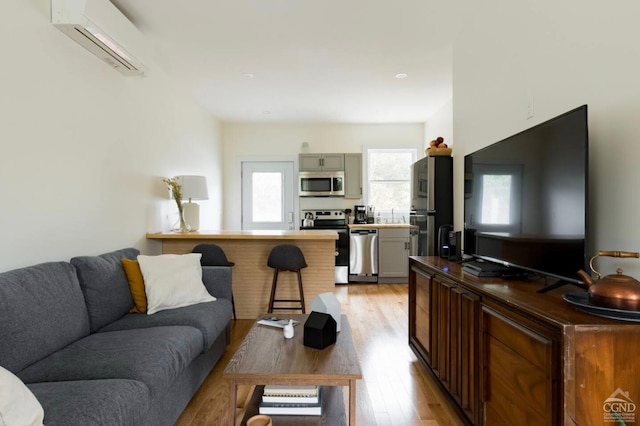 living area featuring light wood-type flooring and an AC wall unit