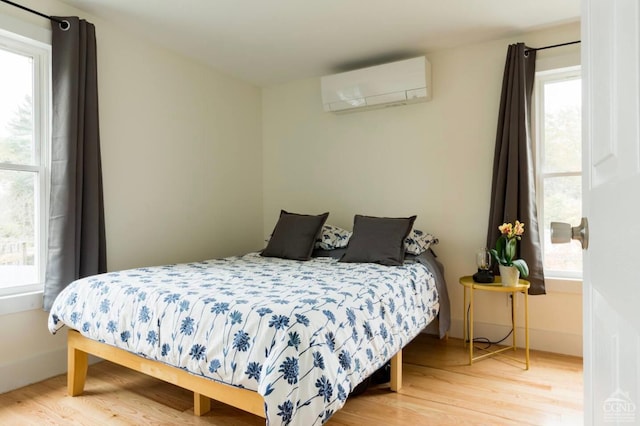 bedroom with a wall unit AC and wood finished floors