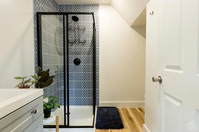 bathroom featuring vanity, baseboards, a shower stall, and wood finished floors