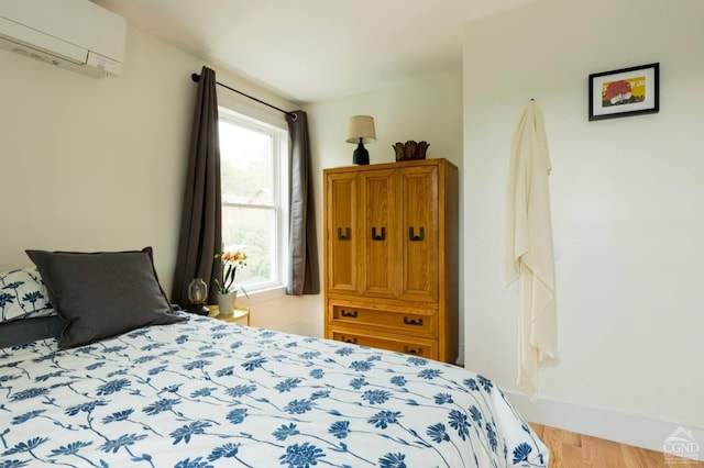bedroom with an AC wall unit and wood finished floors