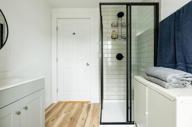 bathroom with vanity, a shower stall, washer / clothes dryer, and wood finished floors