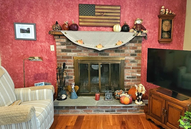 living room with wood-type flooring and a brick fireplace