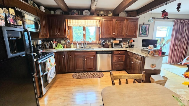 kitchen featuring sink, light stone counters, appliances with stainless steel finishes, kitchen peninsula, and beamed ceiling