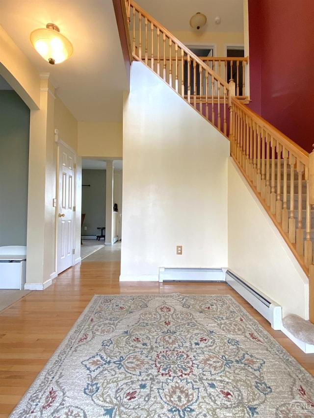 stairway with baseboard heating and hardwood / wood-style flooring