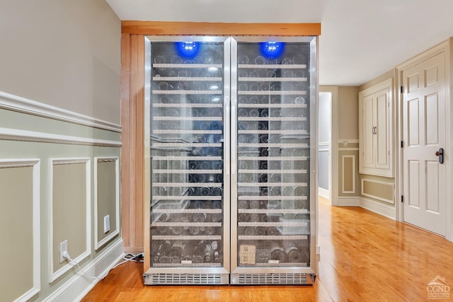 interior details featuring wine cooler, a decorative wall, and wood finished floors