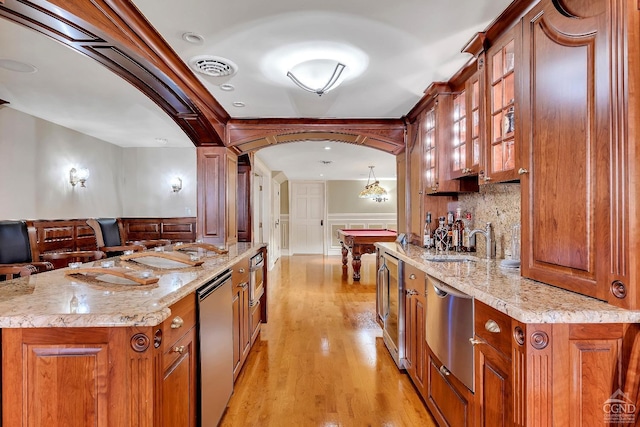 kitchen with dishwasher, brown cabinetry, visible vents, and a sink