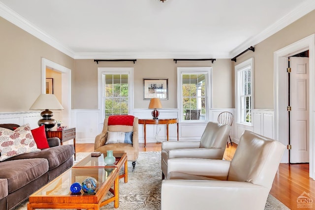 living room featuring wainscoting, a healthy amount of sunlight, crown molding, and wood finished floors