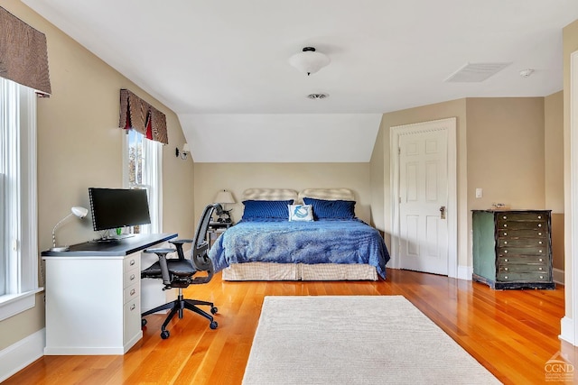 bedroom with visible vents, baseboards, light wood-type flooring, and lofted ceiling