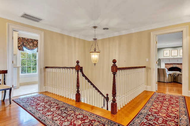 staircase with visible vents, crown molding, and wood finished floors