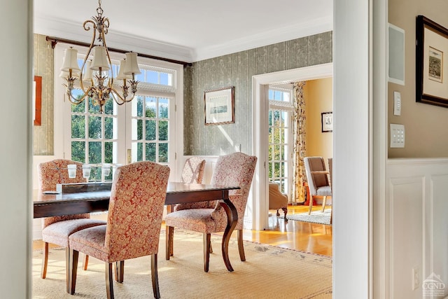 dining area featuring a wealth of natural light, a chandelier, crown molding, and a wainscoted wall