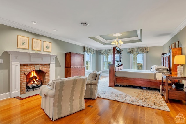 bedroom with wood finished floors, visible vents, a tray ceiling, ornamental molding, and a notable chandelier