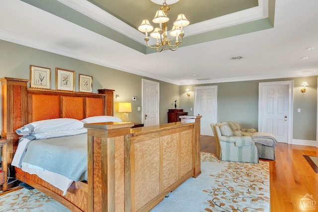 bedroom with light wood-type flooring, a raised ceiling, an inviting chandelier, crown molding, and baseboards