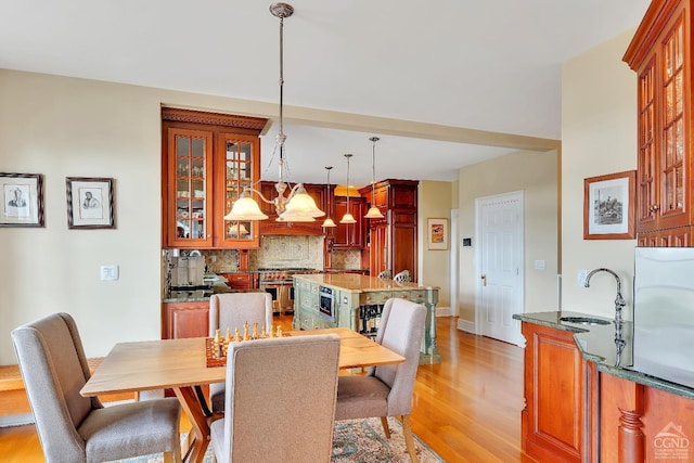 dining area with baseboards, light wood-style floors, and a chandelier