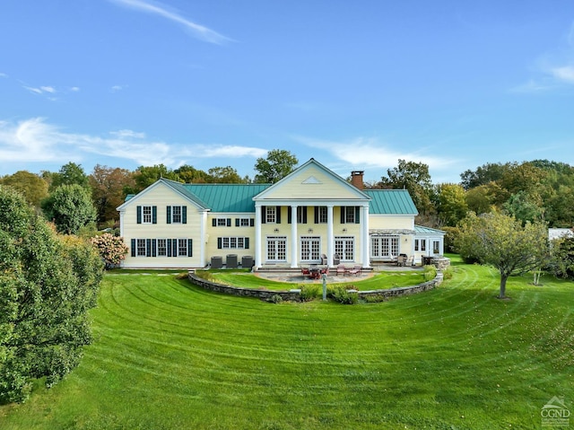 back of property featuring a standing seam roof, a yard, french doors, and metal roof