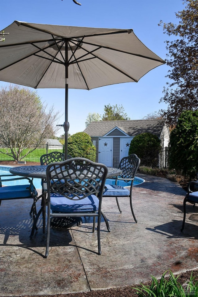 view of patio / terrace featuring fence, an outbuilding, and outdoor dining space