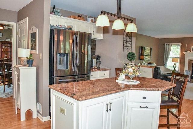 kitchen featuring stainless steel fridge, open floor plan, light wood-style floors, and white cabinets