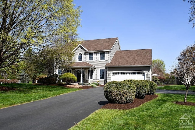 view of front of house featuring an attached garage, a shingled roof, a front lawn, and aphalt driveway