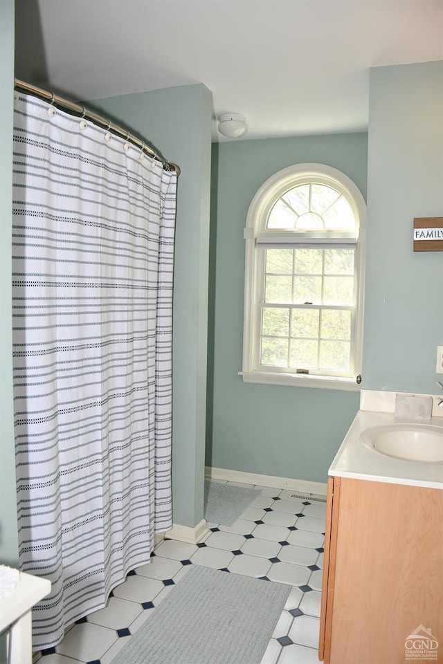full bath with a shower with shower curtain, baseboards, tile patterned floors, and vanity