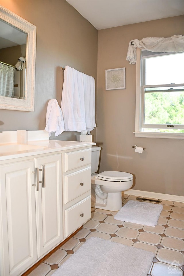 bathroom featuring vanity, toilet, tile patterned floors, baseboards, and visible vents